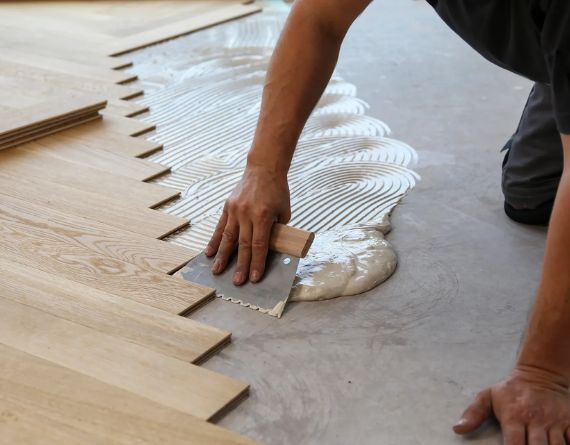 A man working on wood flooring installation in Miami, highlighting the precision and quality of the flooring service provided.