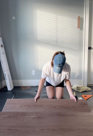 A woman kneeling on a hardwood floor highlights flooring services available in Miami, FL.